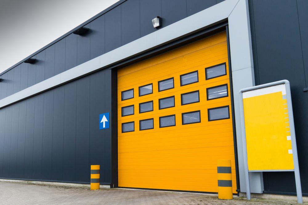 A Large Yellow Garage Door Is On The Side Of A Building — Lighthouse Beach Garage Door Service in Laurieton, NSW