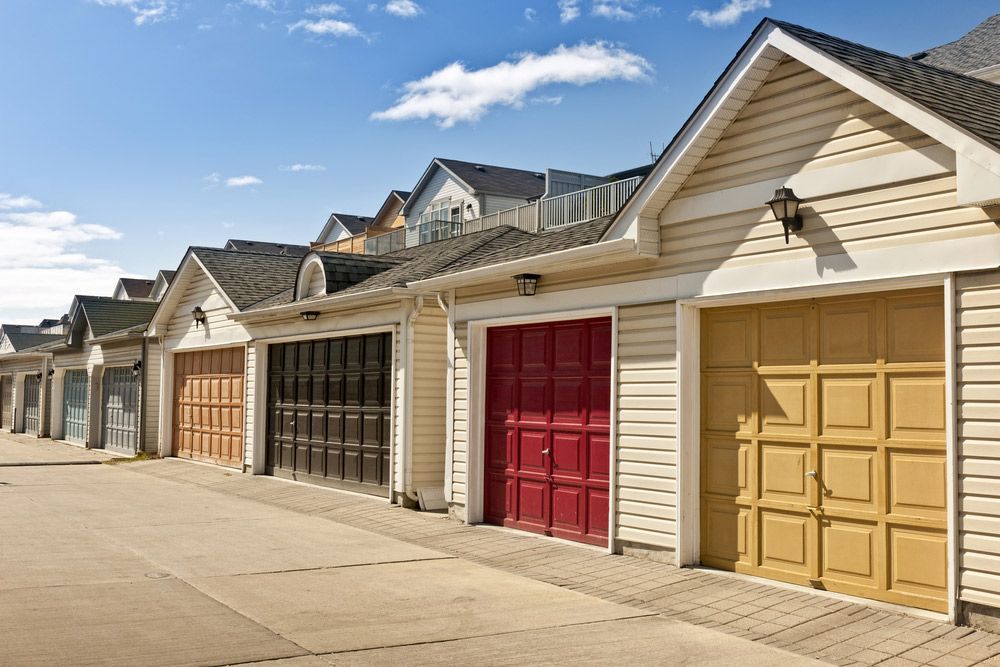 A Row Of Garages With Different Colored Doors Are Lined Up Next To Each Other — Lighthouse Beach Garage Door Service in Laurieton, NSW
