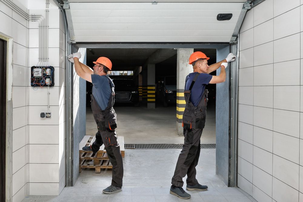 Two Skilled Men Are Installing A Garage Door — Lighthouse Beach Garage Door Service in Port Macquarie, NSW