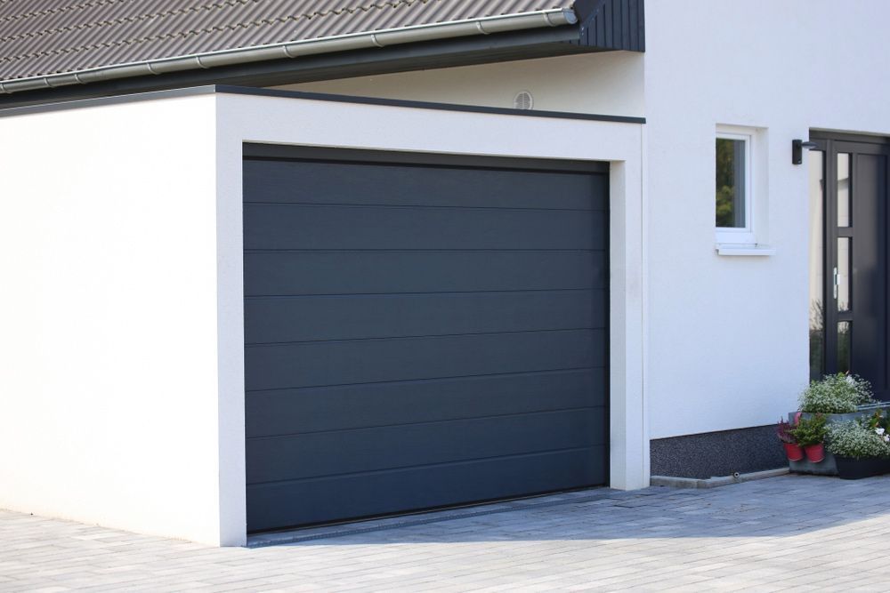 A Black Garage Door Is Installed In Front Of A White House — Lighthouse Beach Garage Door Service in Port Macquarie, NSW