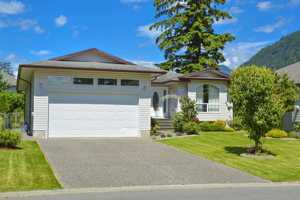 A White House With A White Garage Door And A Driveway — Lighthouse Beach Garage Door Service in Laurieton, NSW