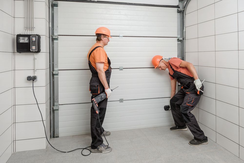 Two Men Are Working On A Garage Door — Lighthouse Beach Garage Door Service in Port Macquarie, NSW