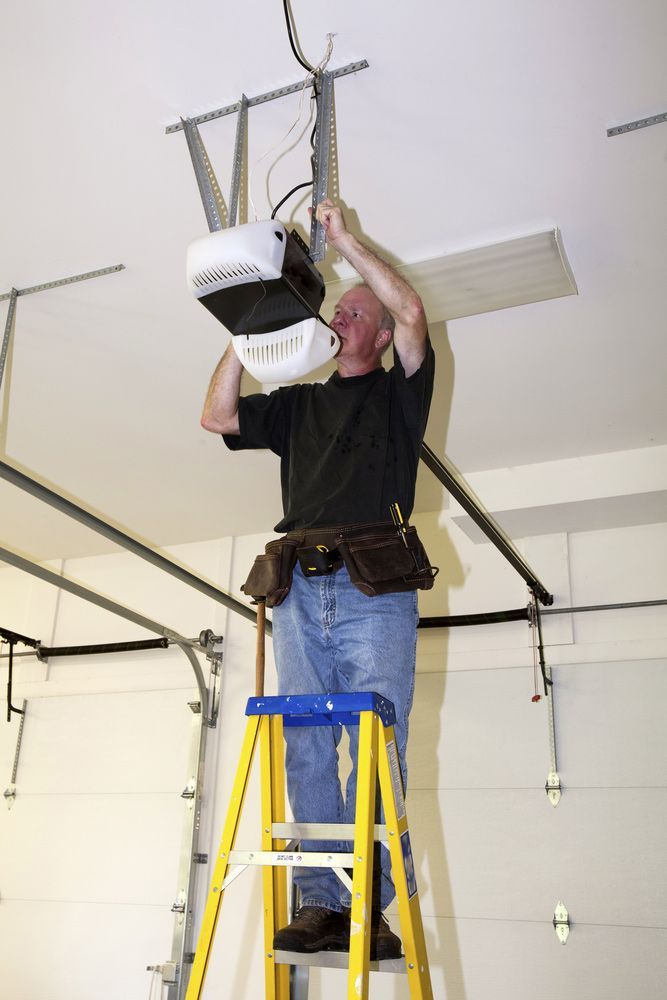 A Skilled Man Is Standing On A Ladder Fixing A Garage Door Opener — Lighthouse Beach Garage Door Service in Port Macquarie, NSW