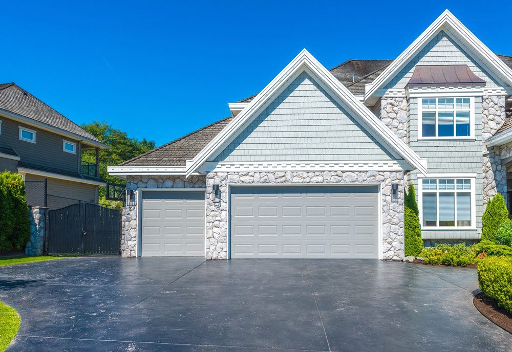 A Large House With Two Garage Doors And A Long Driveway — Lighthouse Beach Garage Door Service in Lake Cathie, NSW