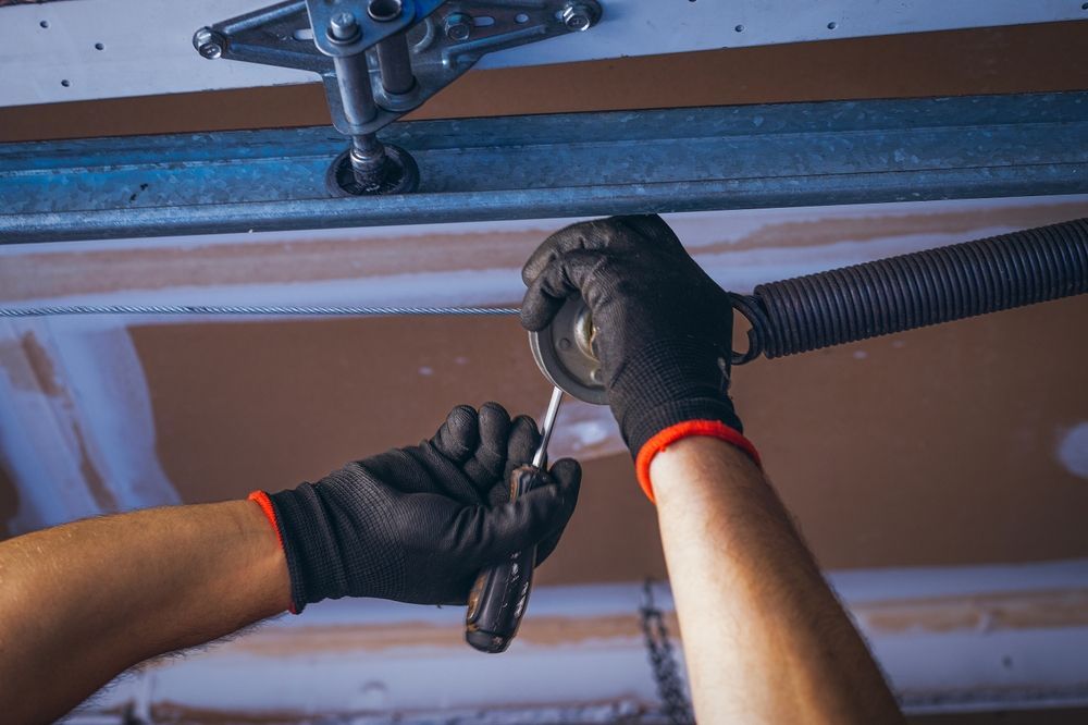 Gloved hands using a ratchet to repair a garage door mechanism — Lighthouse Beach Garage Door Service in Port Macquarie, NSW