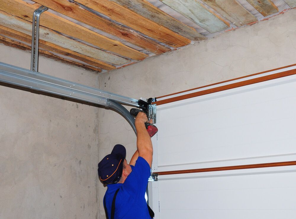 A Man Is Working On A Garage Door With A Drill Machine — Lighthouse Beach Garage Door Service in Port Macquarie, NSW
