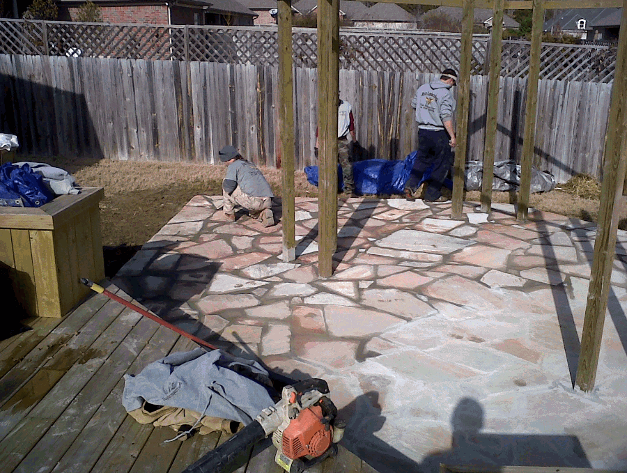 A group of people are working on a stone patio