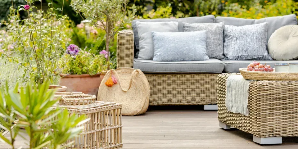 A wicker patio set with a couch , table , and potted plants.