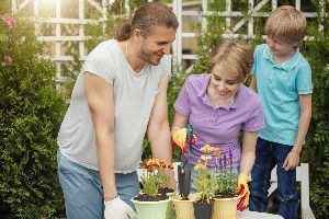 A family is planting flowers in pots in a garden.