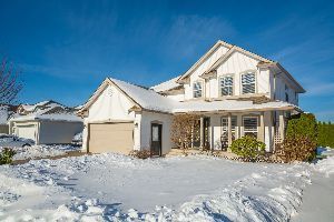 A large white house covered in snow on a sunny day.