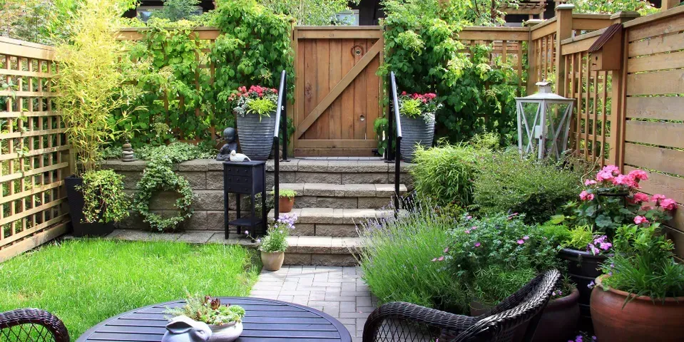 A small backyard with a table and chairs and a wooden gate.