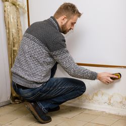 A man is cleaning a wall with a sponge.