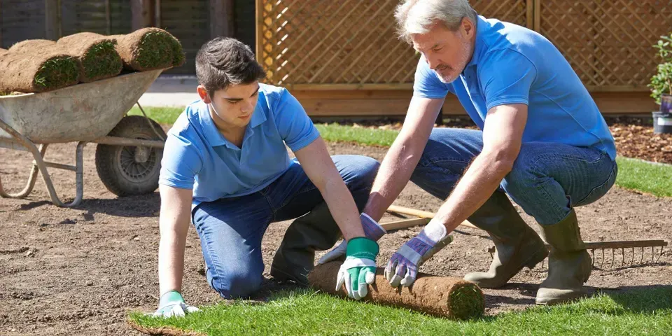 A man and a boy are working on a lawn.