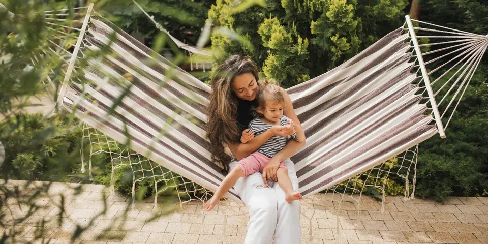 A woman is holding a baby in a hammock.