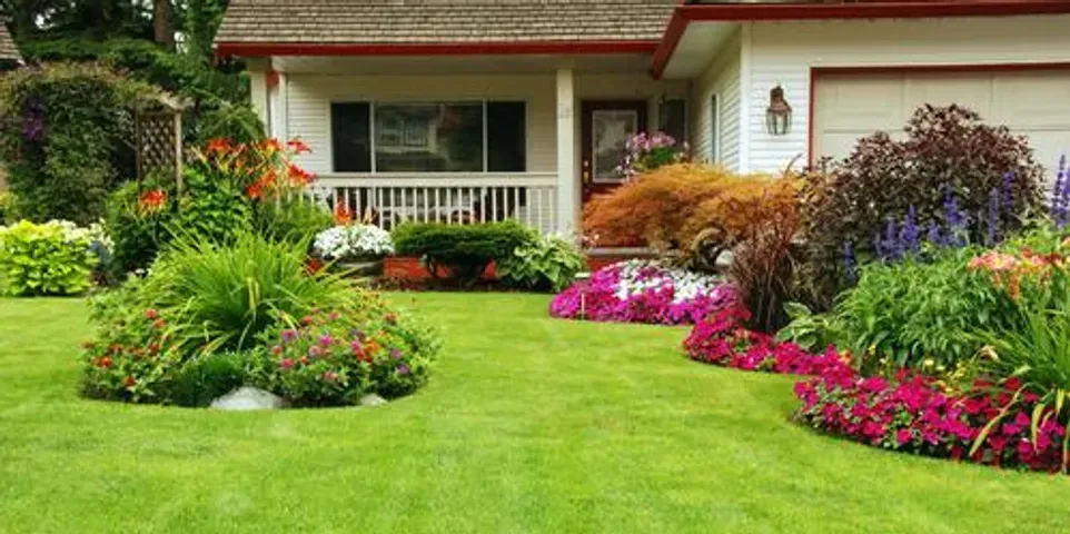 A house with a lush green lawn and flowers in front of it.