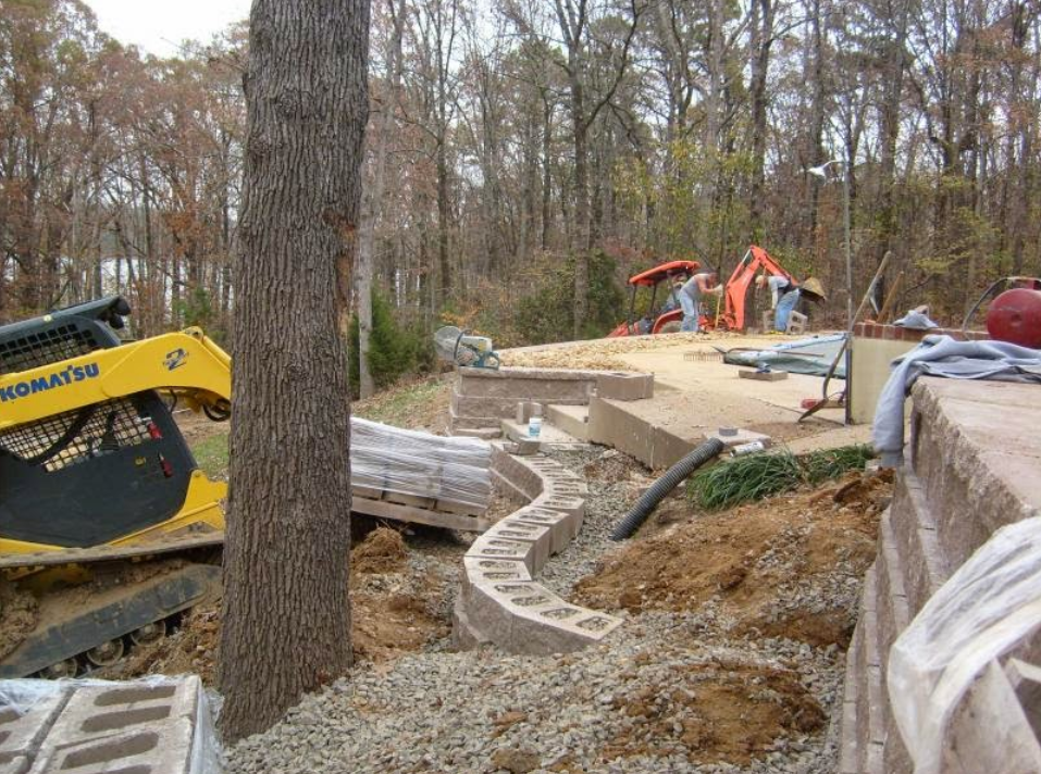 A yellow komatsu excavator is sitting in the dirt next to a tree.