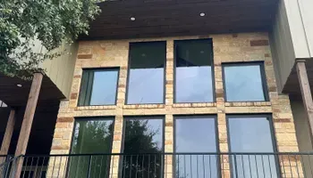 Modern brick building facade with large windows and a balcony under a dark overhang