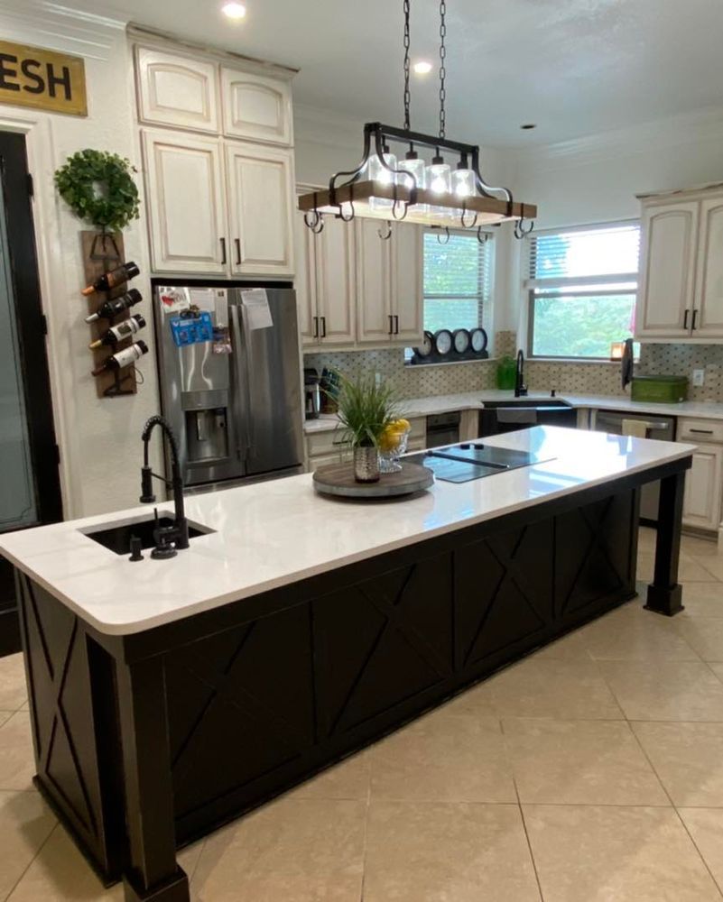 Modern kitchen with large island, white cabinets, black accents, pendant lights, and tiled floor