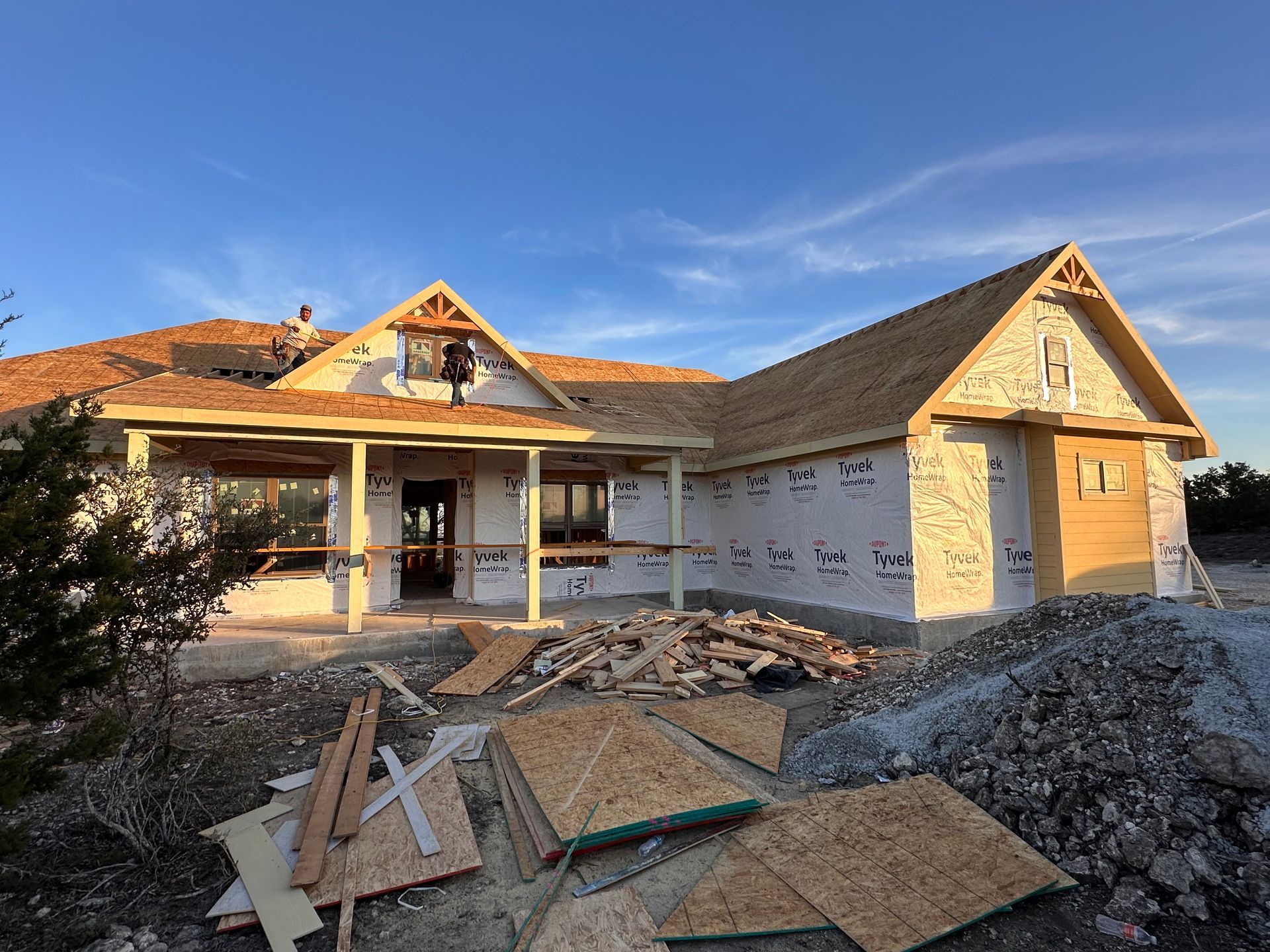 Partially built house with yellow siding and roof under construction, debris in the foreground.