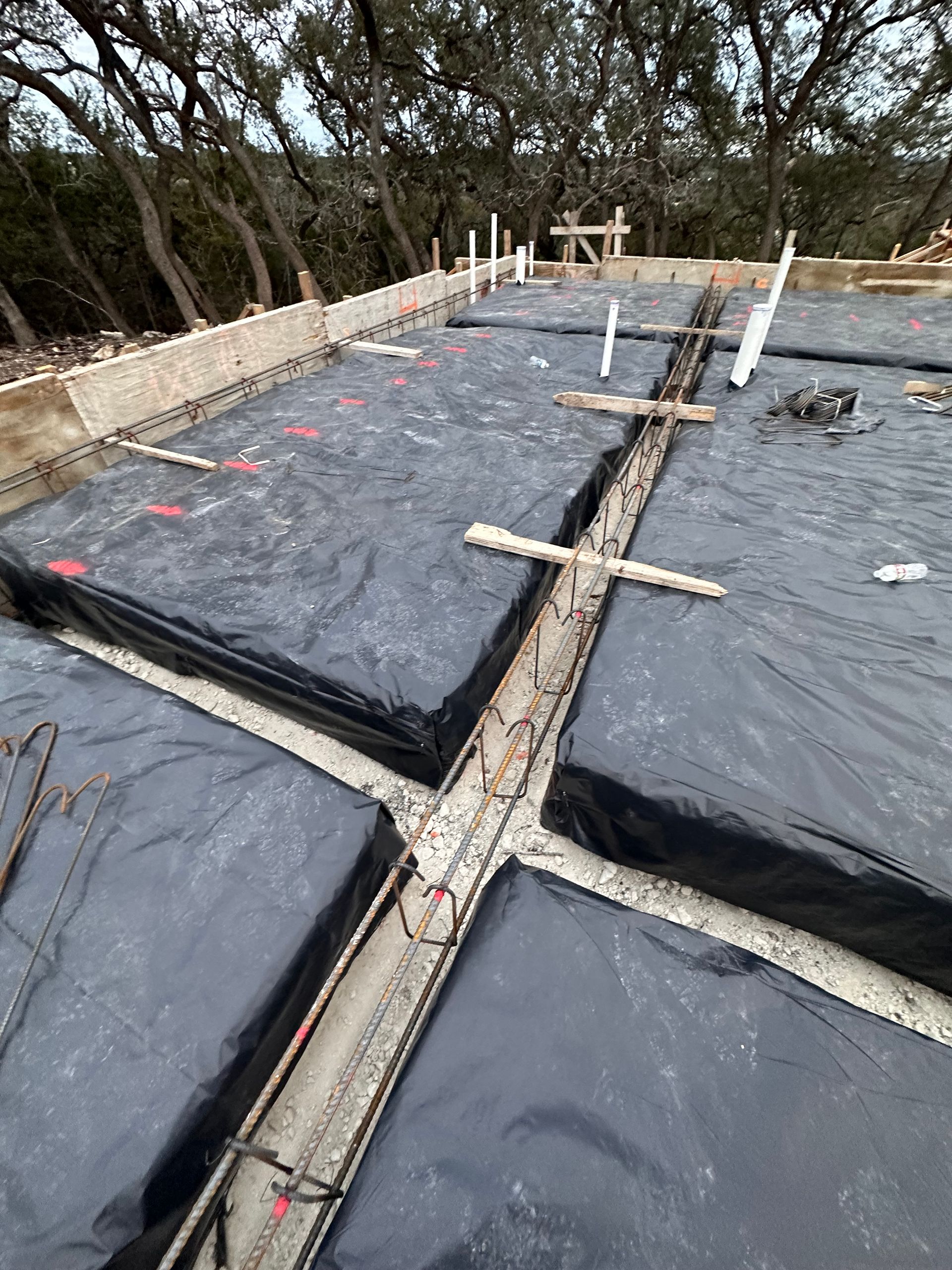 Roof under construction with black waterproof membrane, wooden braces, and stone perimeter walls