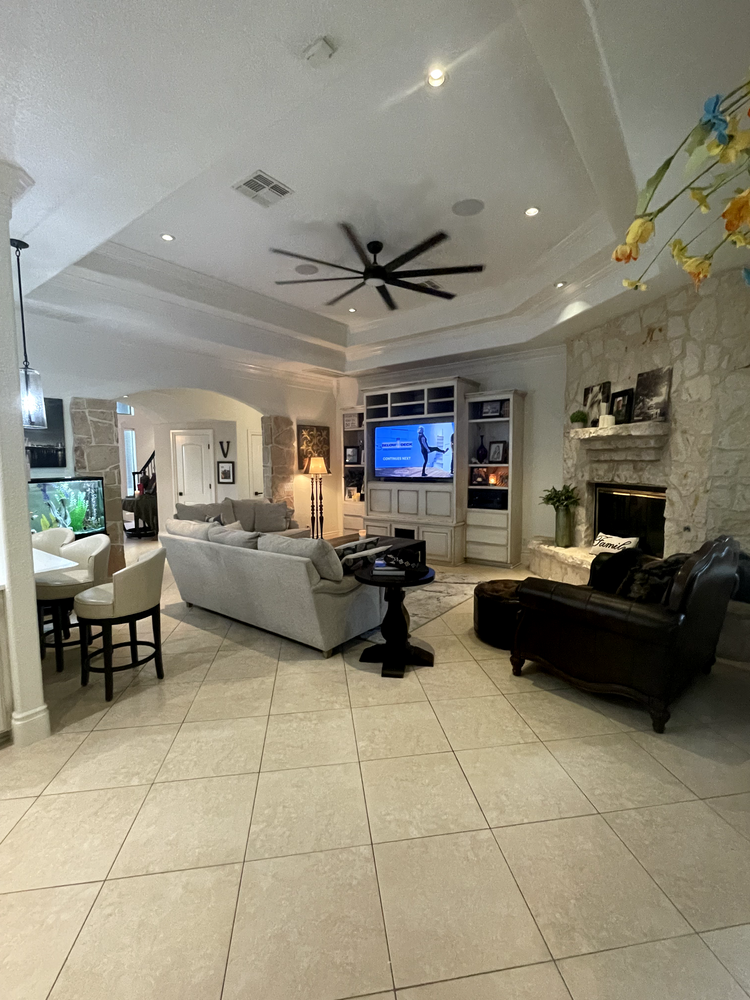 Spacious modern living room with white sectional sofa, black chairs, fireplace, and large ceiling fan.
