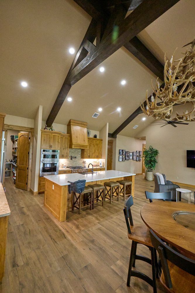 Spacious rustic kitchen and dining area with wood beams, island seating, and warm lighting