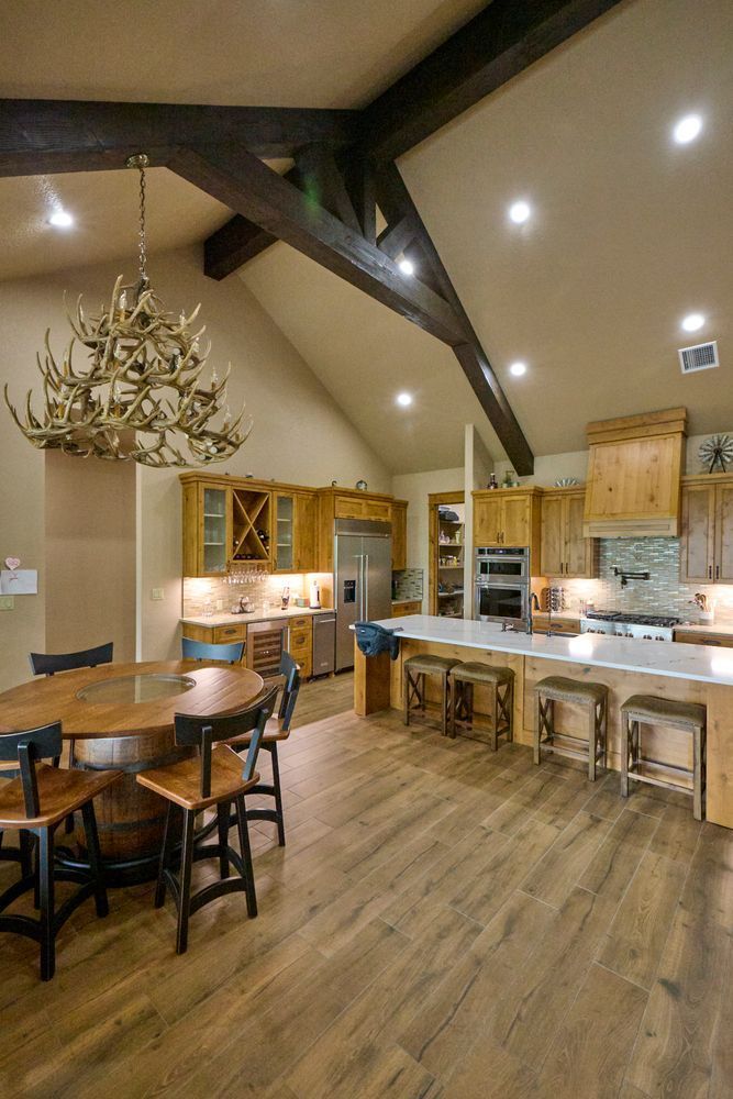 Warm kitchen with wood cabinets, vaulted ceiling, dining table, and island with stools under recessed lights