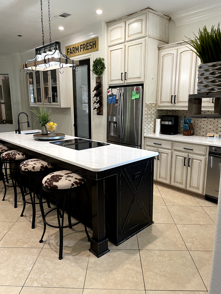 Modern kitchen with white cabinets, black island, barstools, and stainless-steel appliances
