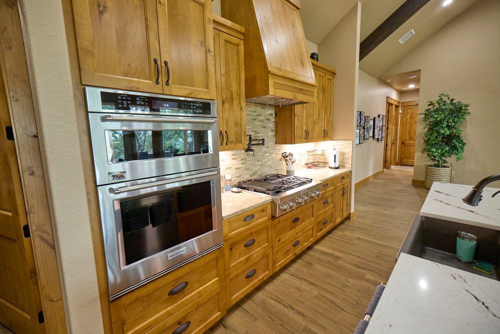 Modern kitchen with wood cabinets, stainless steel oven, granite counters, and a hallway leading to the back.