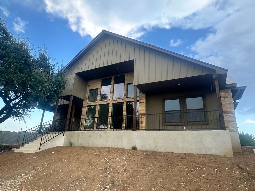 Modern house with wood and metal exterior on a dirt slope under a blue sky