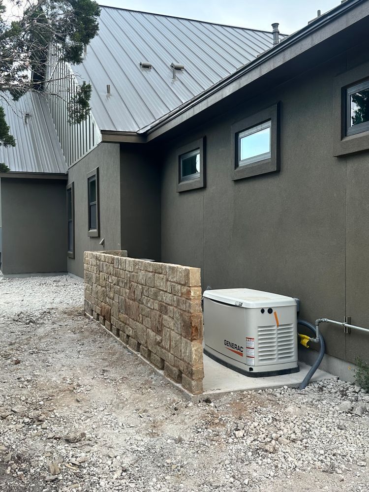Modern house exterior with metal roof, gravel side yard, stone wall, and HVAC unit beside windows