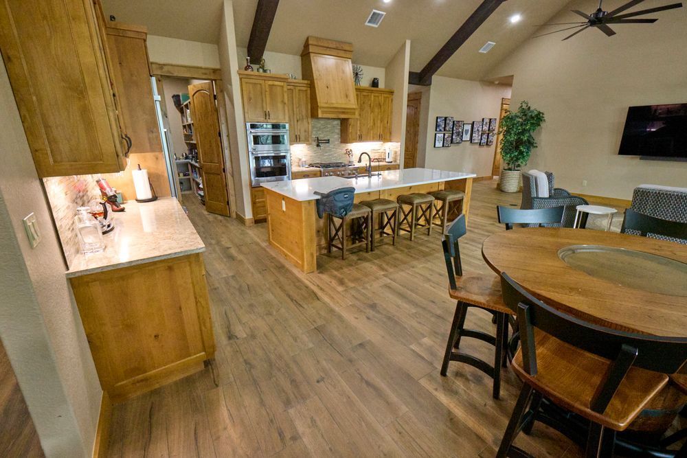 Modern kitchen and dining area with wood cabinetry, island seating, and round table in warm lighting