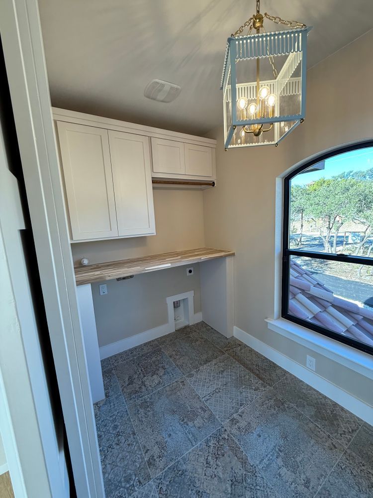 Bright small office nook with built-in cabinets, desk, gray carpet, and a large arched window.