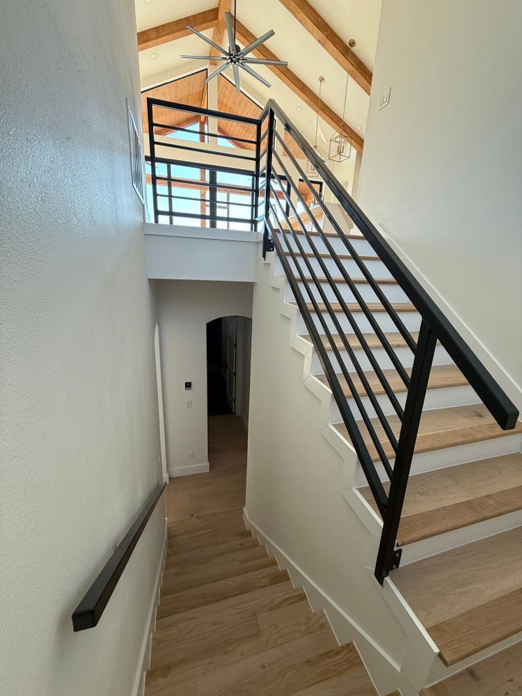 Stairwell with wooden steps, black railing, and vaulted ceiling in a modern interior