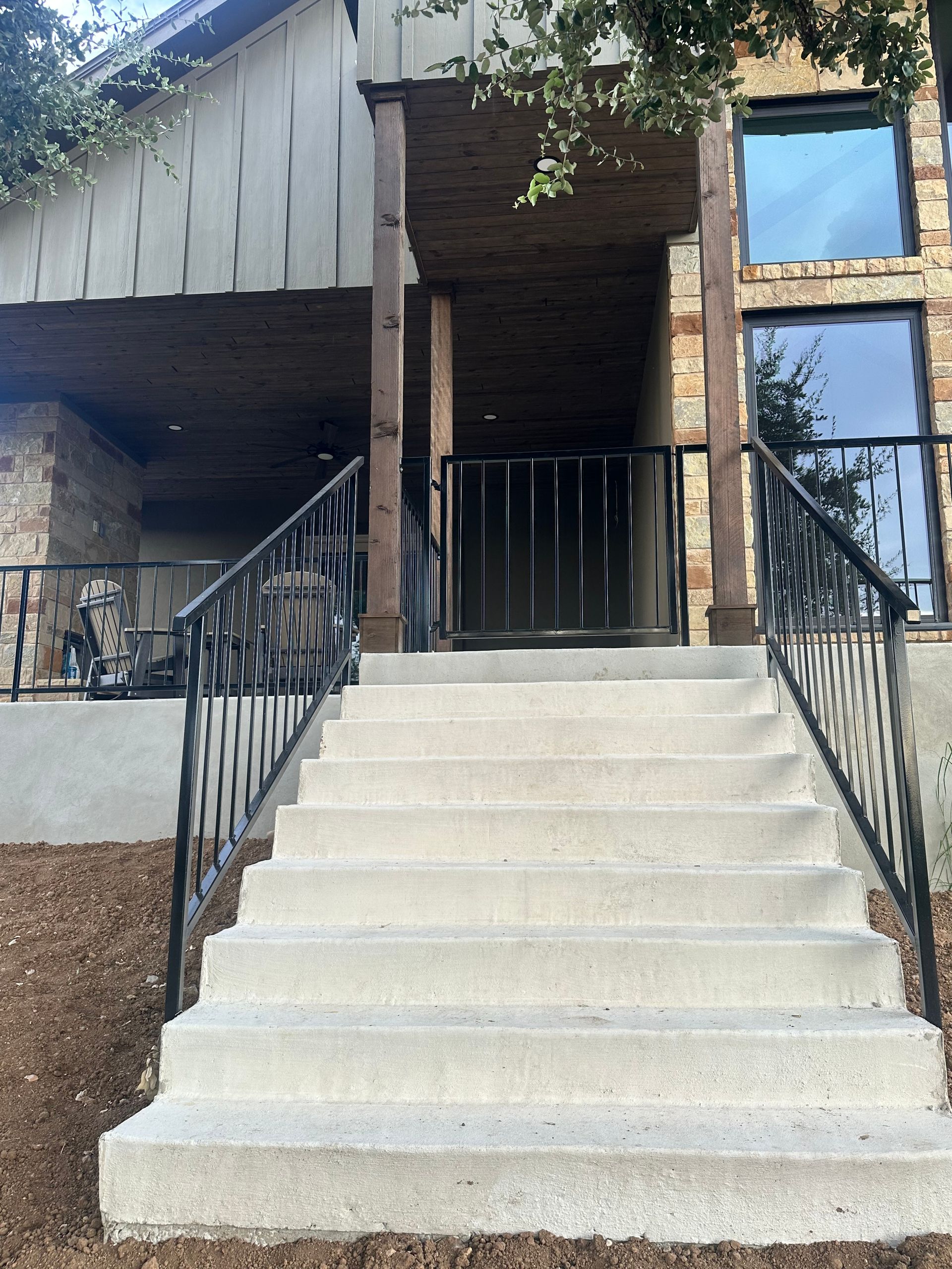 Front entrance with wide concrete steps, black railings, and brick-and-siding exterior.