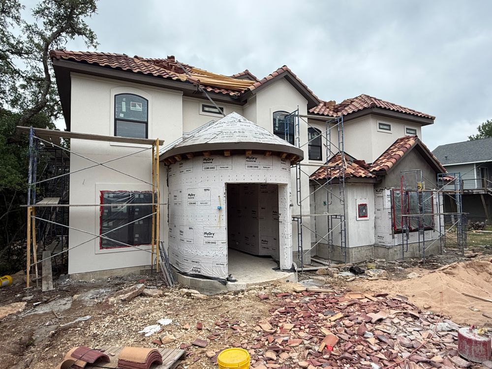 Partially demolished two-story house with exposed framing and construction debris in front
