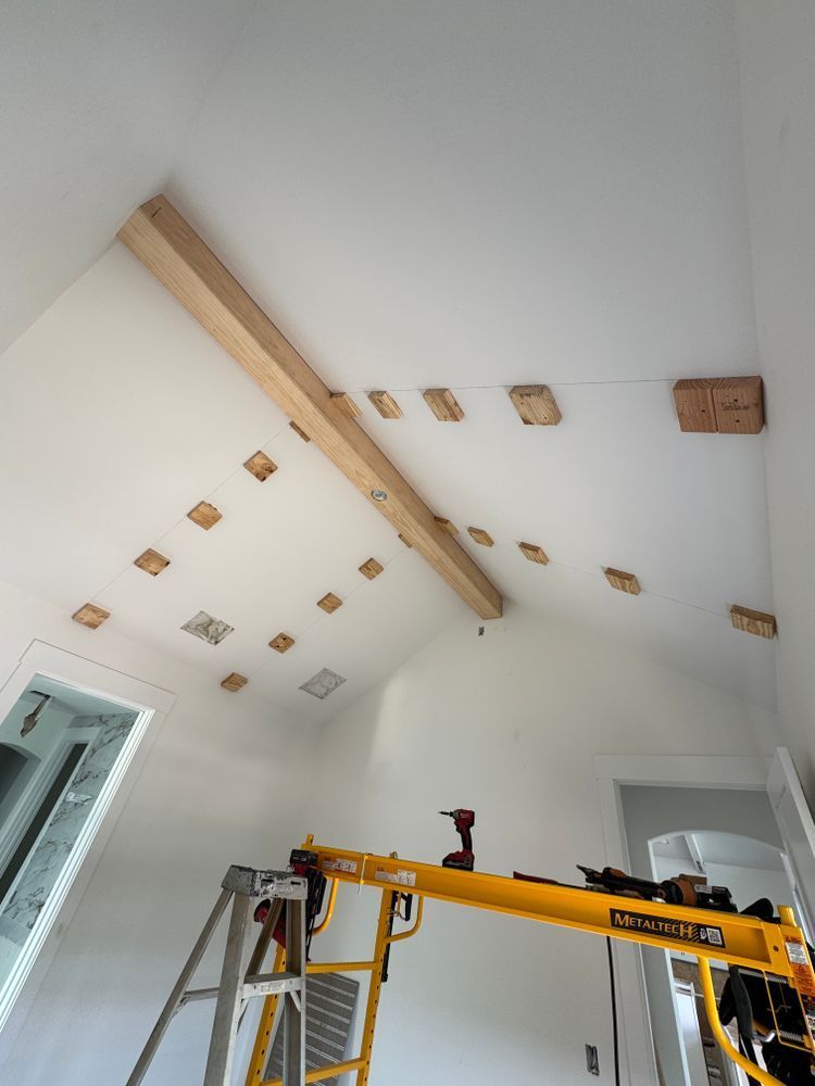Interior room with slanted ceiling, exposed wood beam, and a ladder and lift used for ceiling work