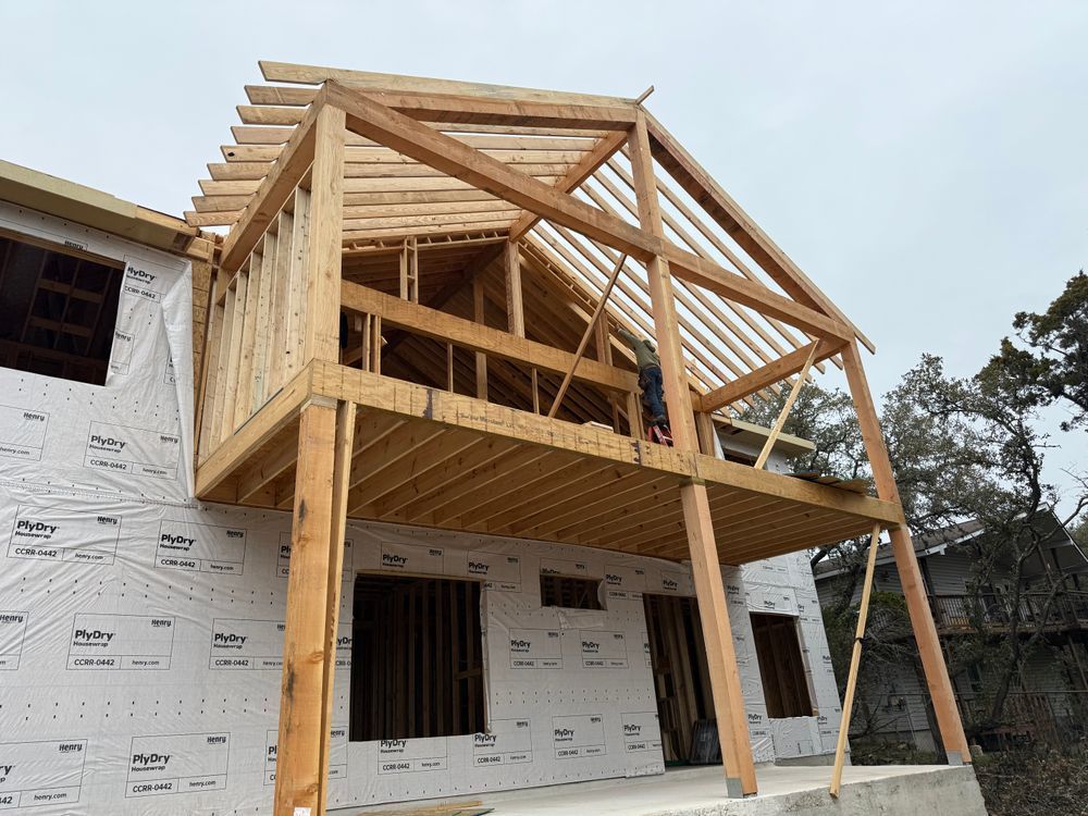 Partially built two-story house with exposed wood framing and wrapped lower walls