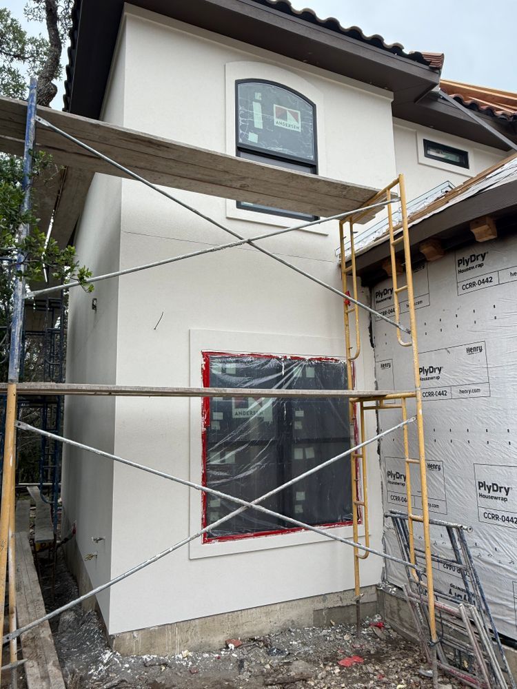 House exterior under construction with white walls, scaffolding, and covered windows