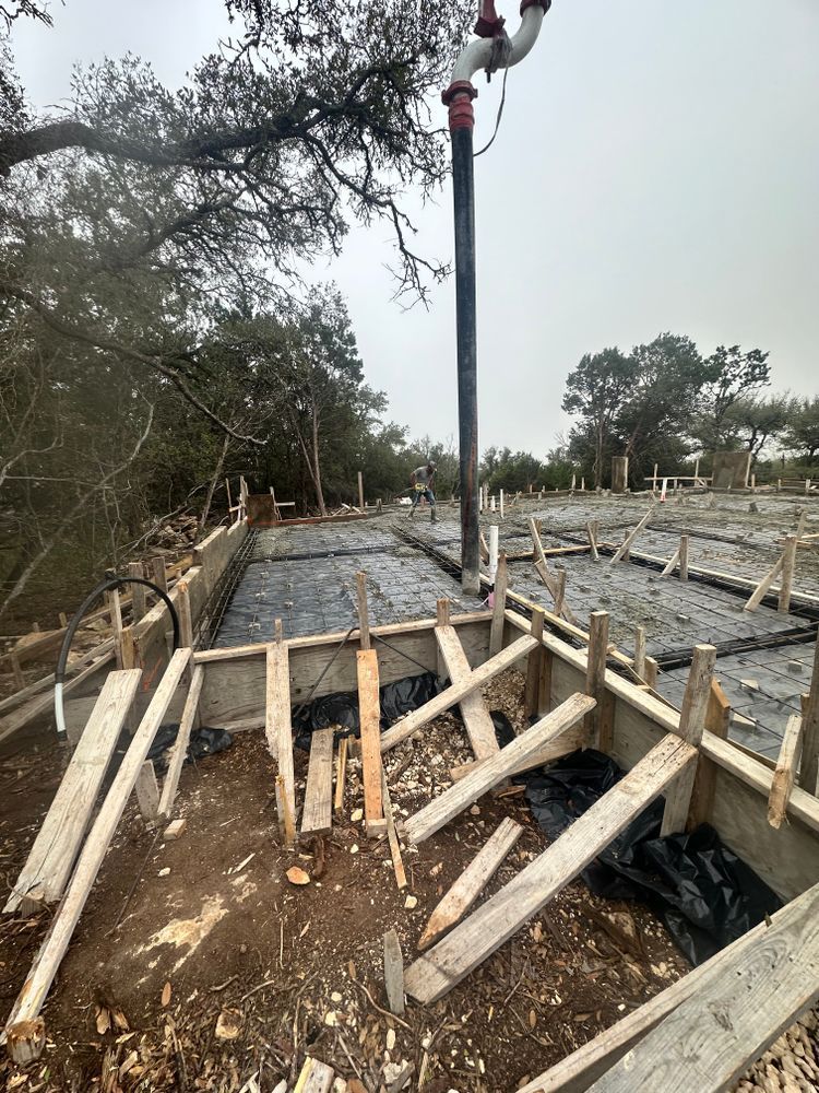 Damaged concrete foundation with fallen wooden forms and a crane in the center at a construction site