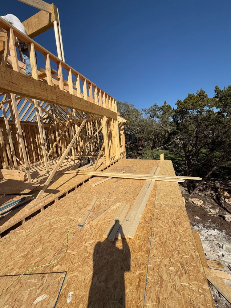 Wood-framed house under construction with plywood flooring and a clear blue sky