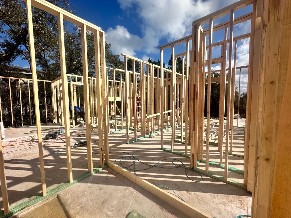 Wood-framed house under construction with open wall studs and blue sky above