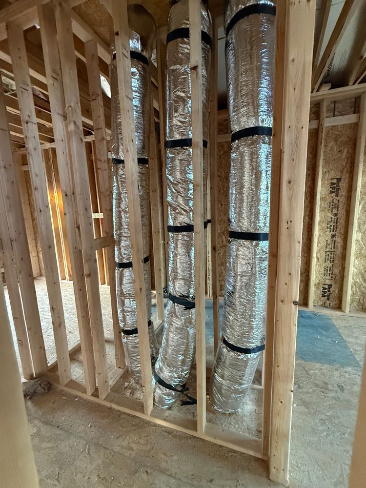 Framed house interior with insulated HVAC ducts and unfinished wooden studs