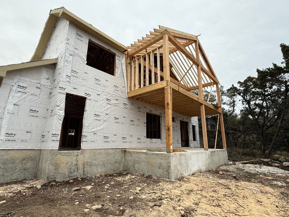 Partially finished white house with exposed wooden framing on the upper floor under cloudy sky