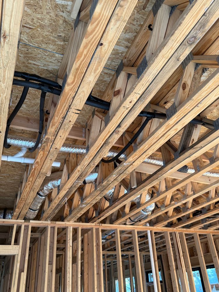 Exposed wooden ceiling joists and insulation above unfinished interior framing under construction