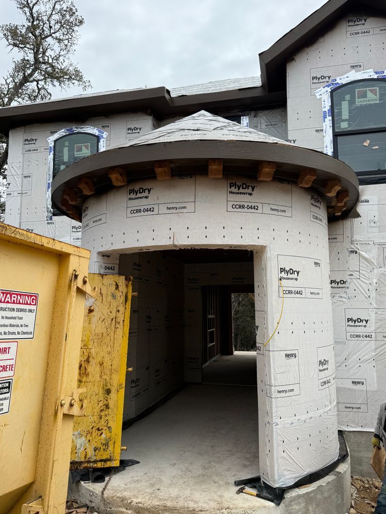 Front entrance of a house under construction, with wrap and exposed wood framing.