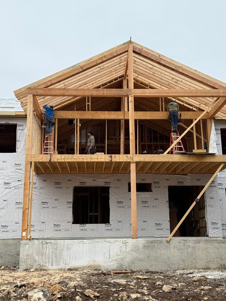Partially built house with exposed wooden framing and workers on the upper floor