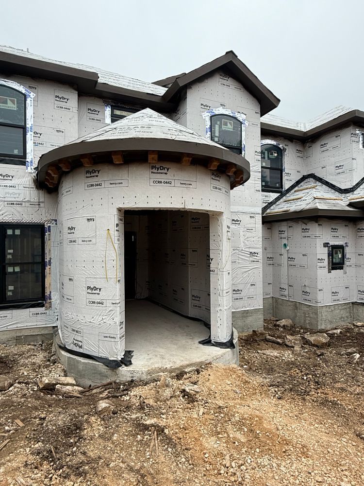 Partially built house exterior with white wrapped walls and an unfinished front entryway