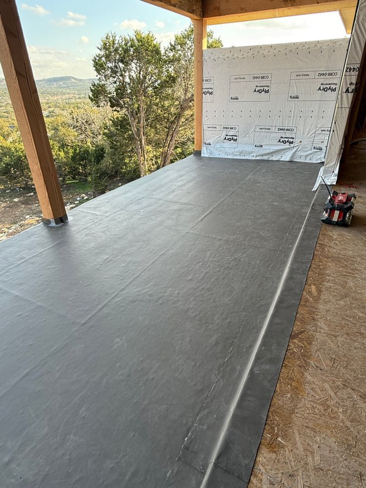 Outdoor covered porch with a long gray floor covering and a white wall board at the far end