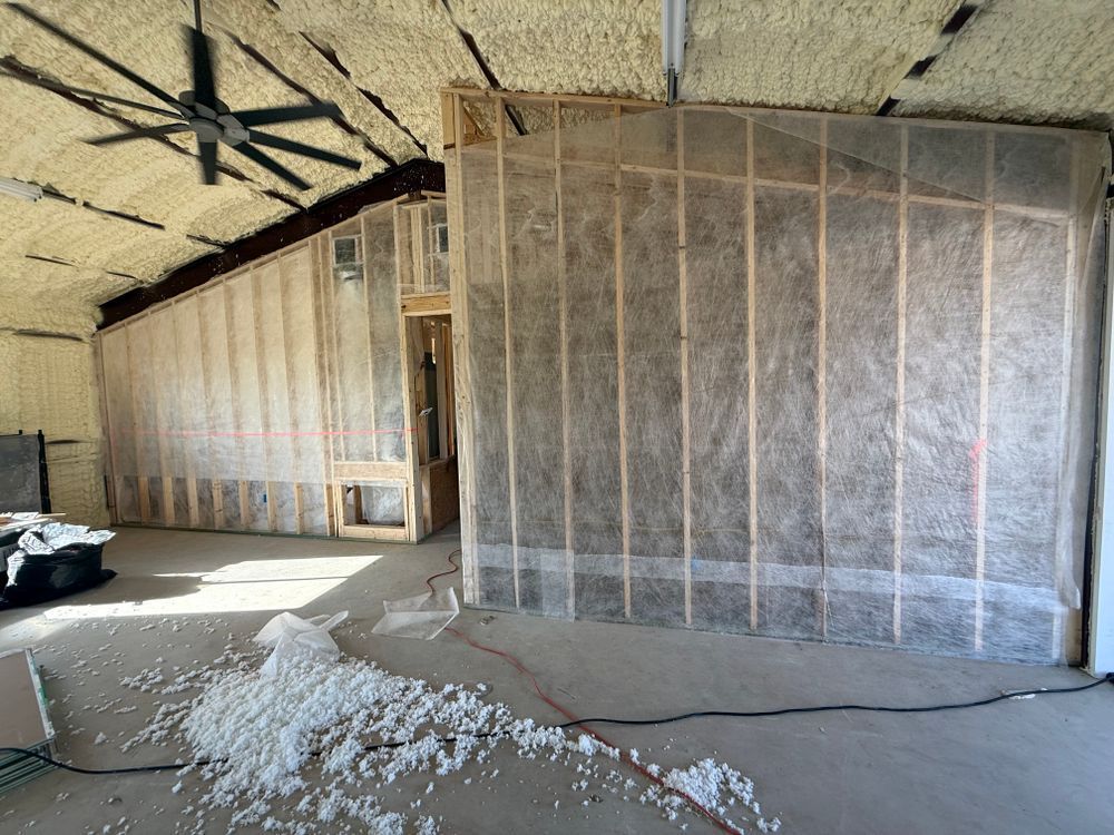 Attic under renovation with exposed framing, insulation, and scattered foam debris on the floor